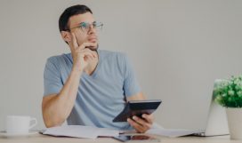 o-homem-pensativo-serio-usa-oculos-redondos-calcula-extensoes-usa-computador-laptop-generico-e-calculadora_95891-1114